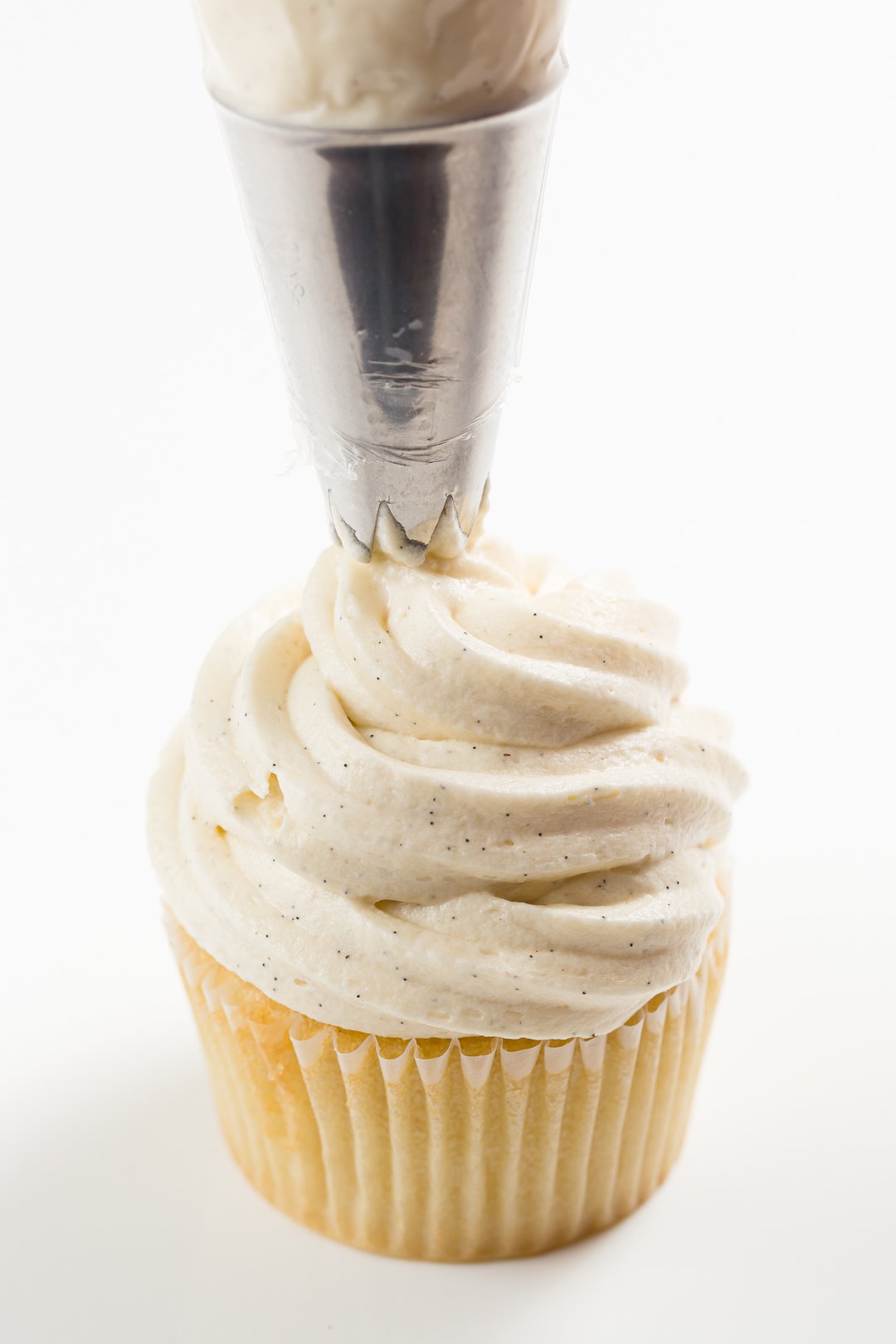 Piping sour cream frosting on a cupcake