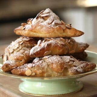 Easy Almond Croissants piled high on a green cake plate
