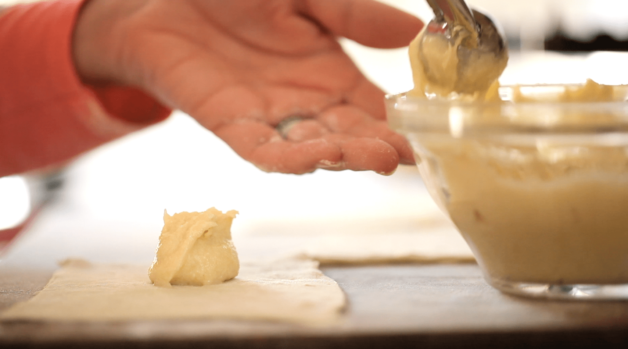 almond filling being scooped onto croissant dough for an almond croissant recipe