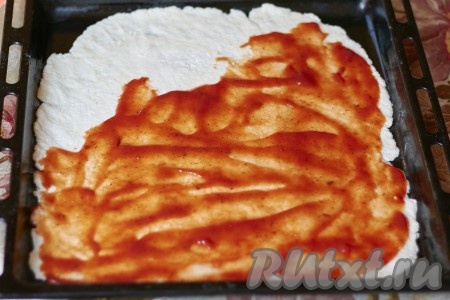 Тонко раскатываем тесто (толщиной 2-3 мм) и выкладываем на противень. Хорошо смазываем тесто томатной пастой или кетчупом.
